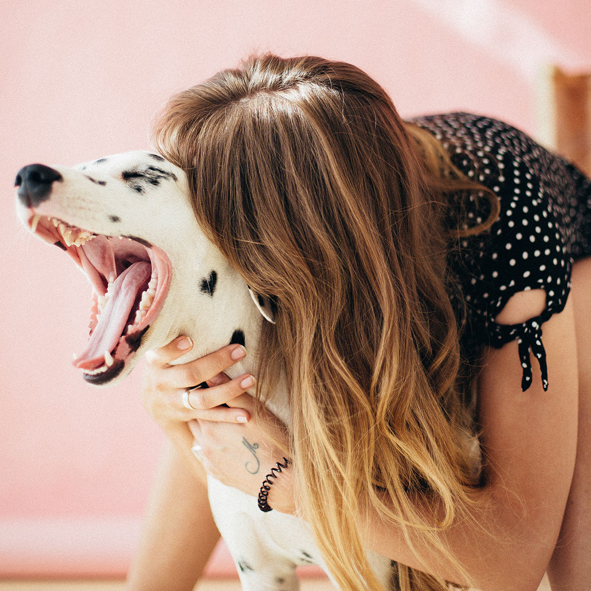 Woman hugging her dog while it yawns.